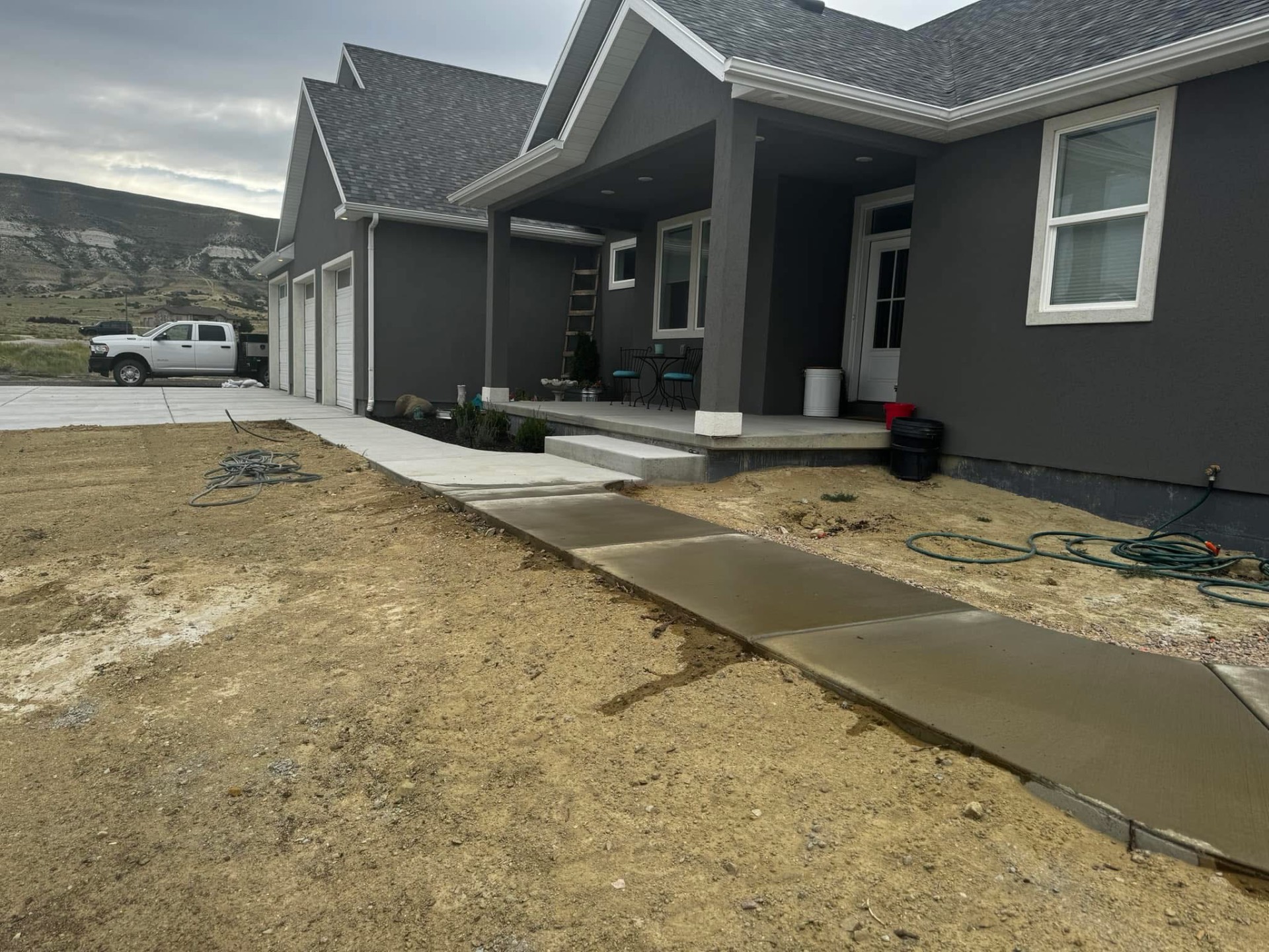 New concrete walkway running to the covered front entry of a home.
