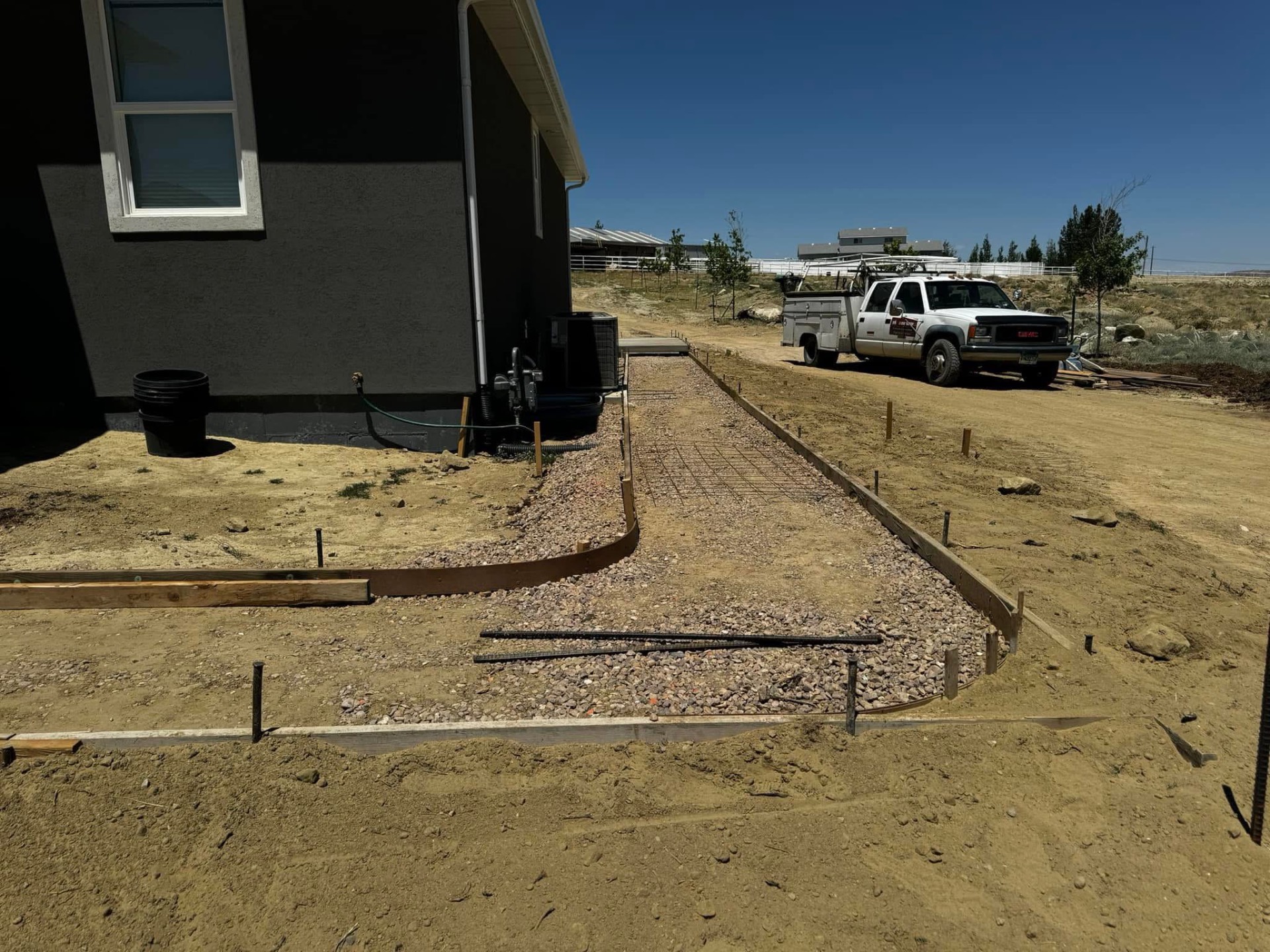 Formed and reinforced gravel base ready for a residential concrete walkway beside a home.