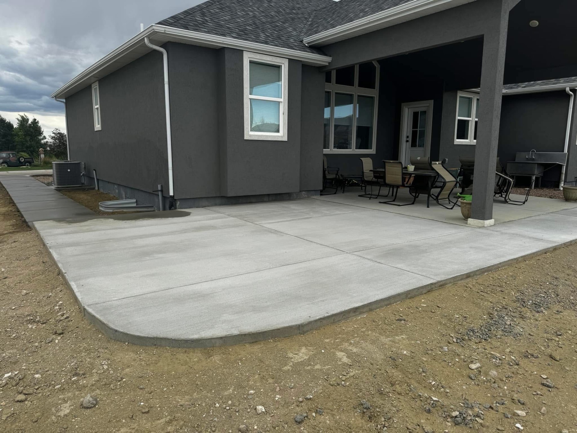 Finished concrete patio slab extending from a covered rear porch.