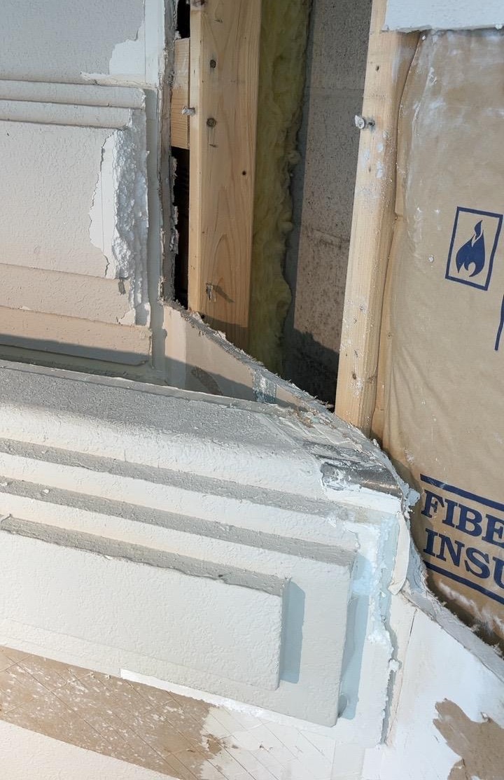 Exterior wall opened at a trim detail exposing framing and insulation before repair.