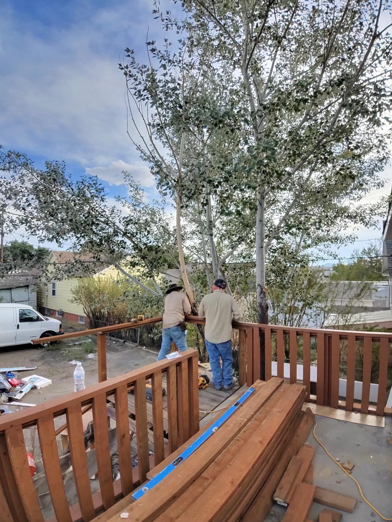 Two crew members setting a stained wood railing on a residential deck under rebuild.