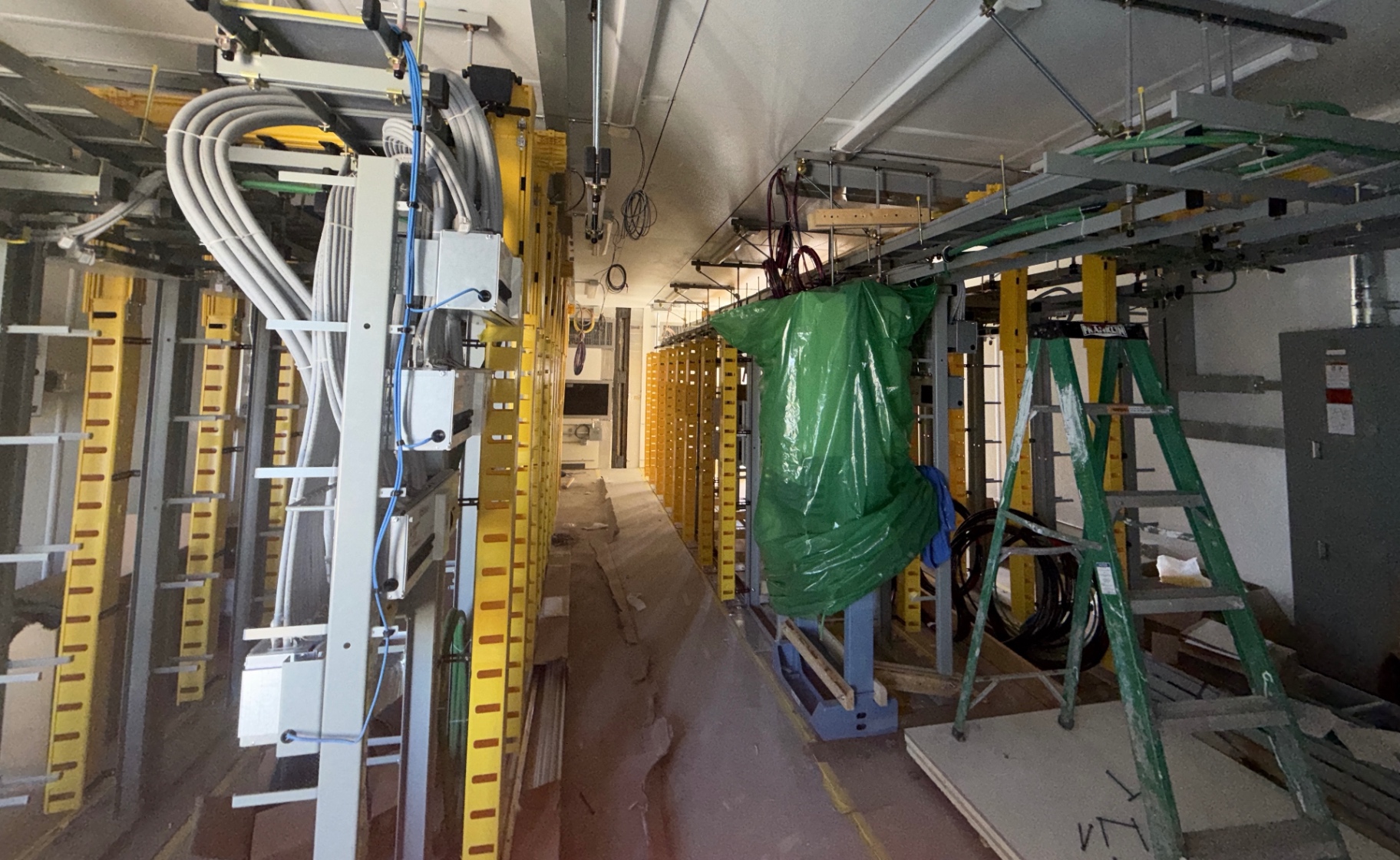 Interior construction support in a data facility corridor, with cable systems and equipment installed by other trades visible in place.