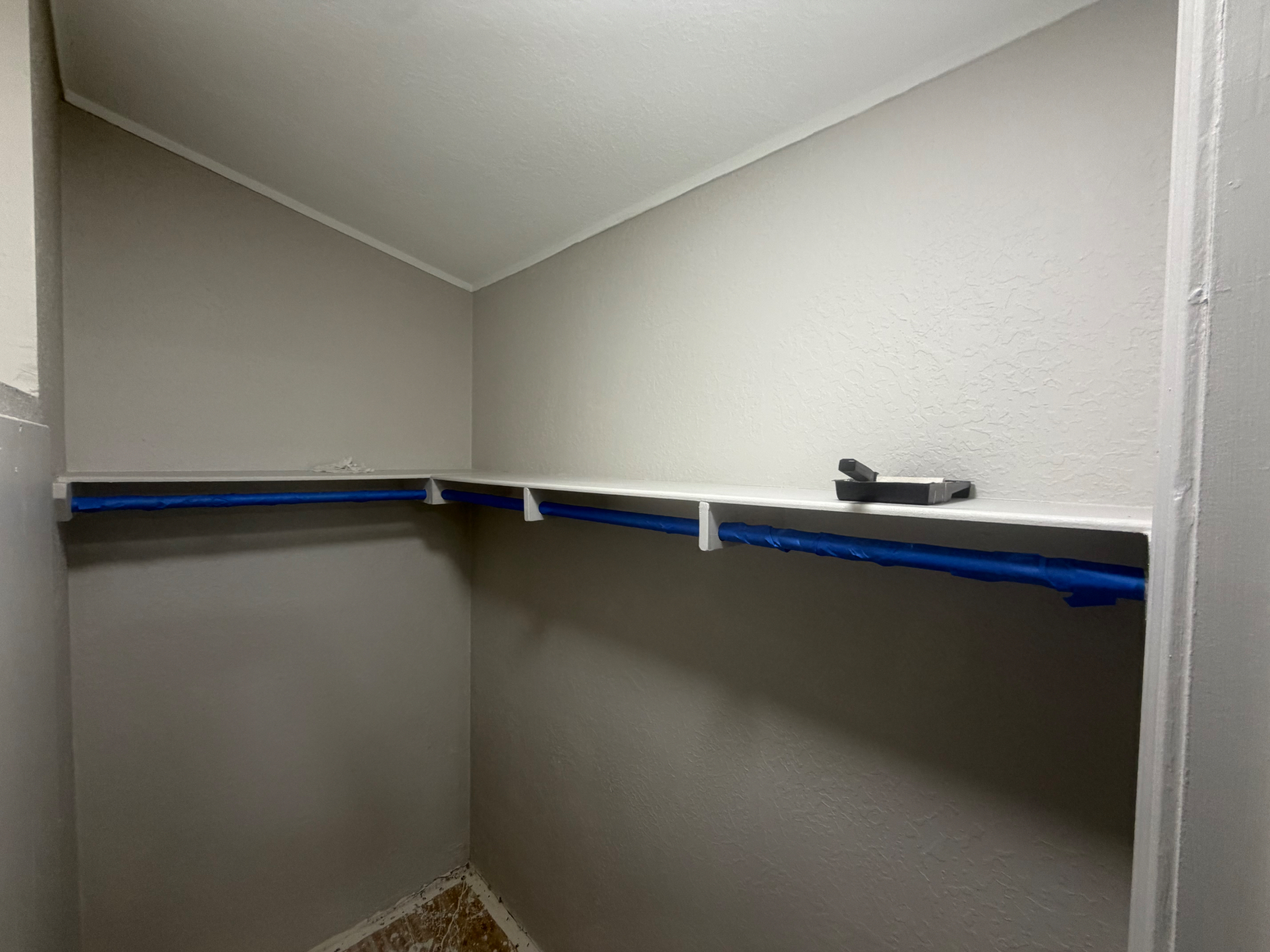 Freshly painted closet with newly installed shelf and hanging rod.