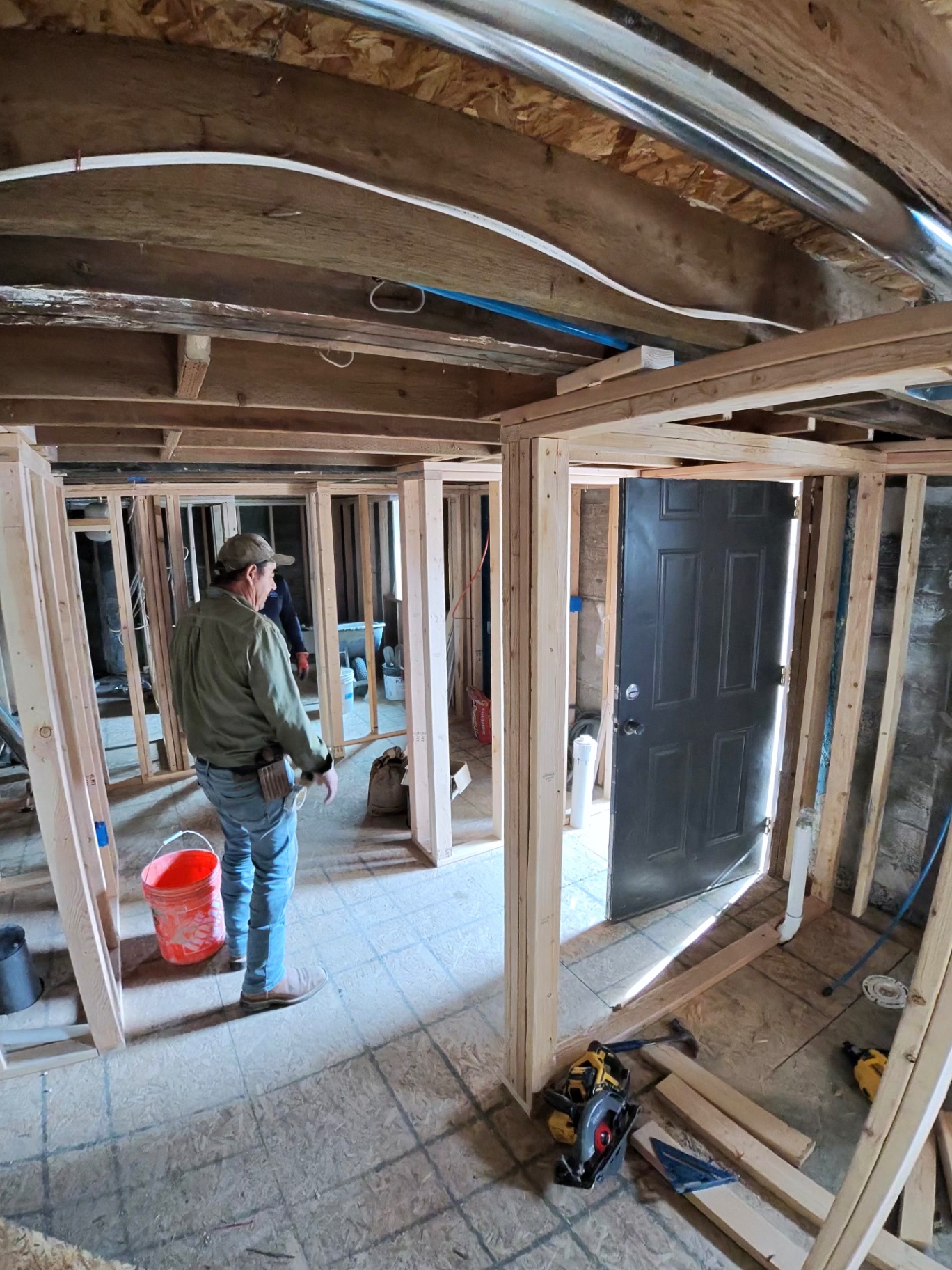 Crew member reviewing newly framed interior walls and door openings during a remodel.