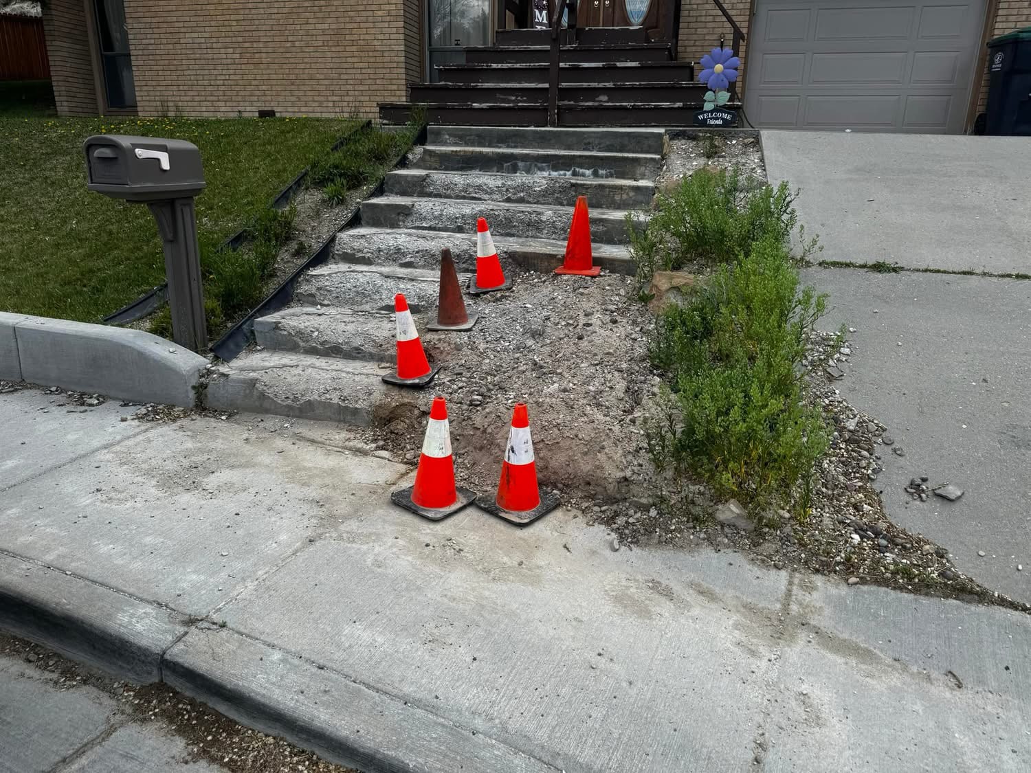 Residential entry steps and walkway removed with cones set around the work area.