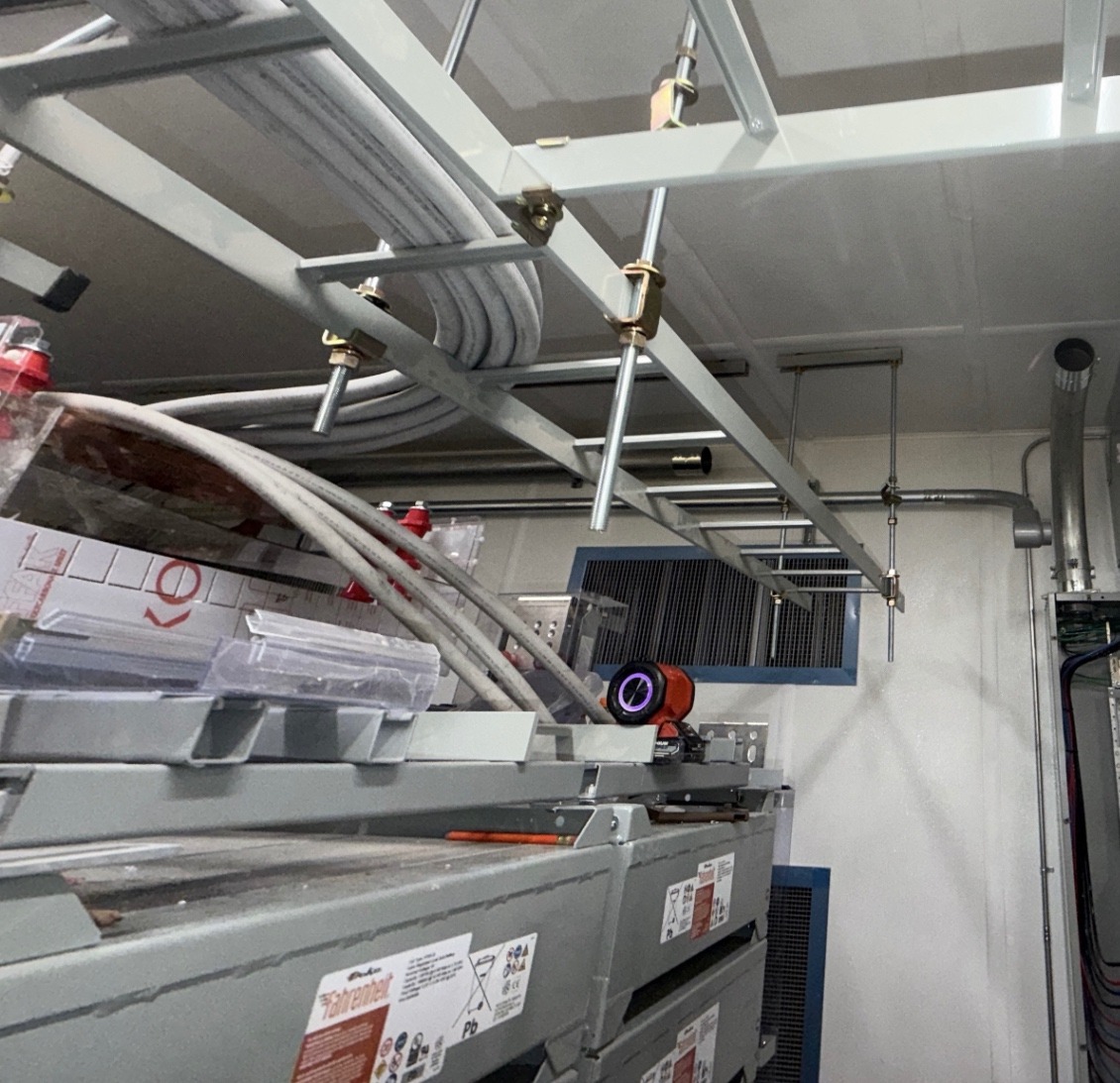 Overhead framing construction support inside a facility room, with conduit installed by another trade visible in place.