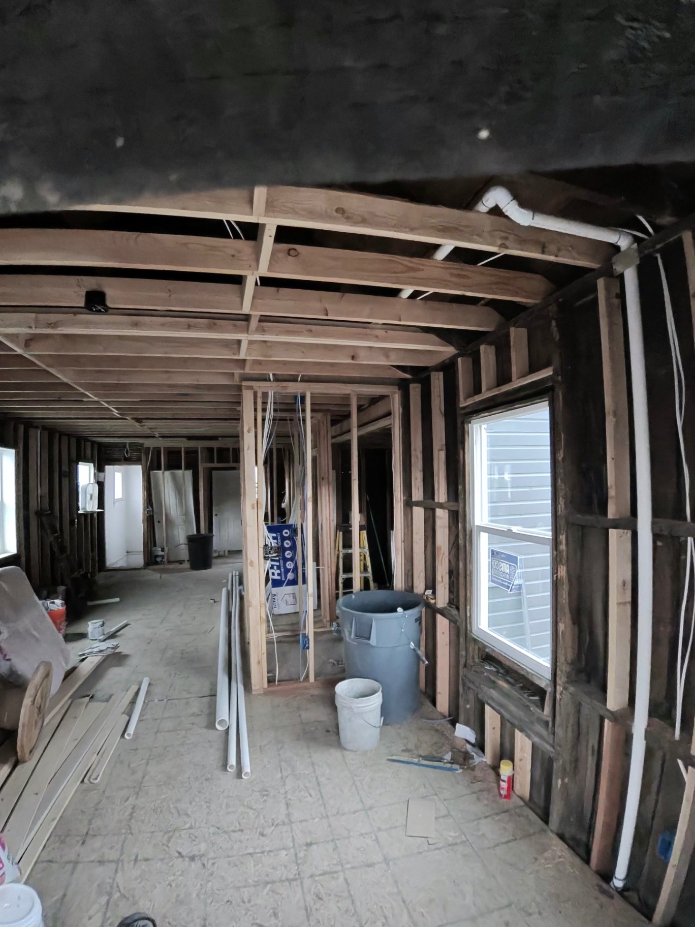 Interior stripped to studs and subfloor with new framing and rough-in materials staged.