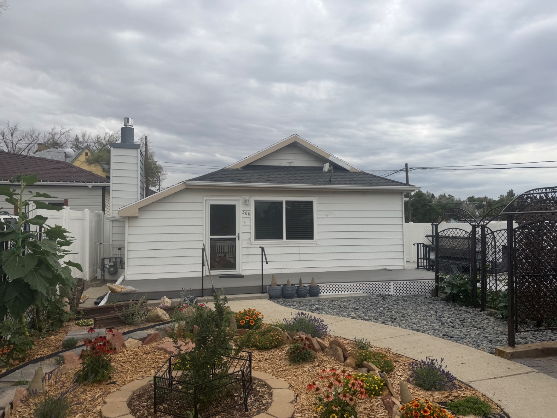 Finished white-sided home with a low deck, skirting and landscaped walkway.