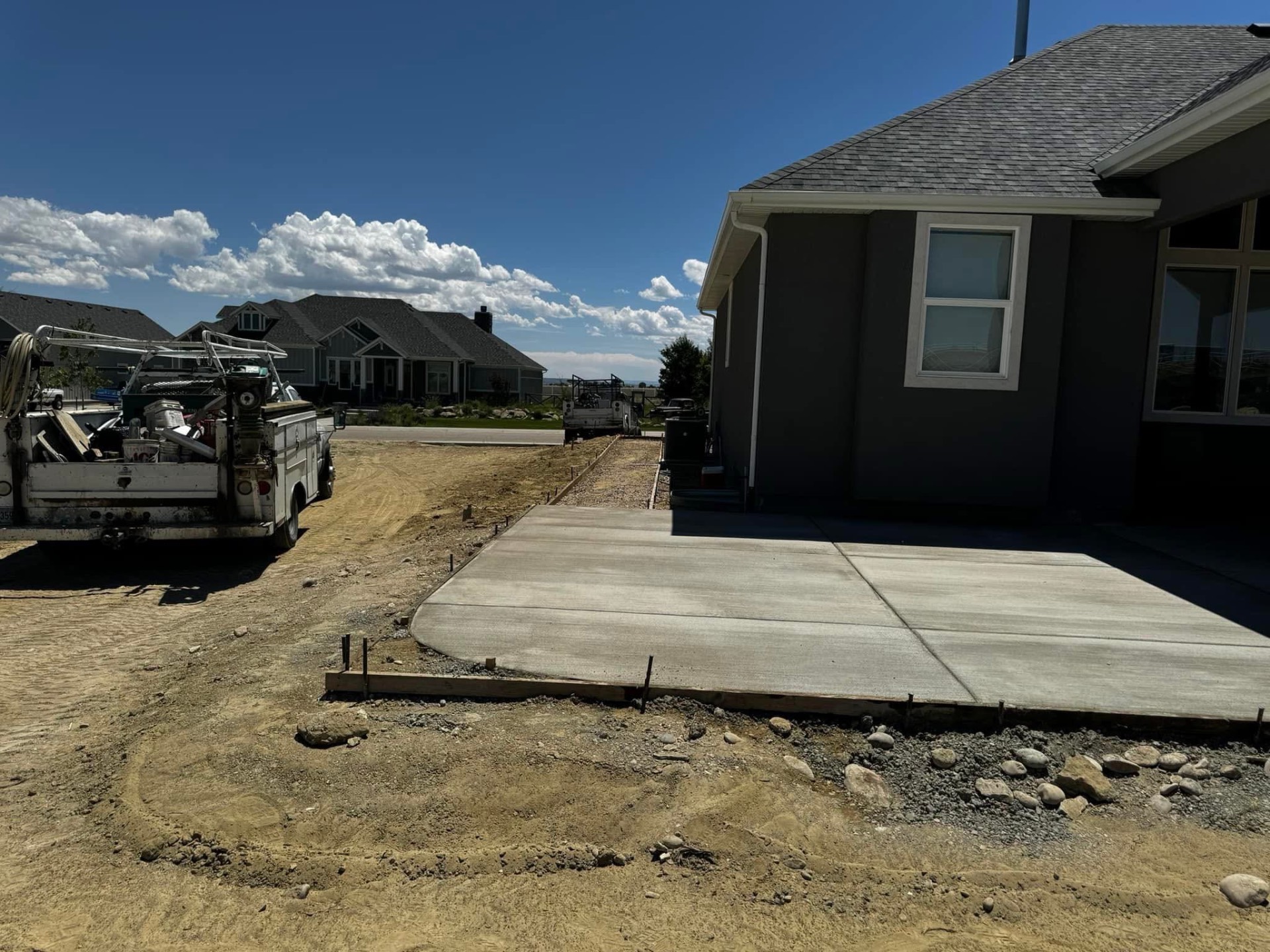 Finished concrete slab and sidewalk along the side of a newly built home.