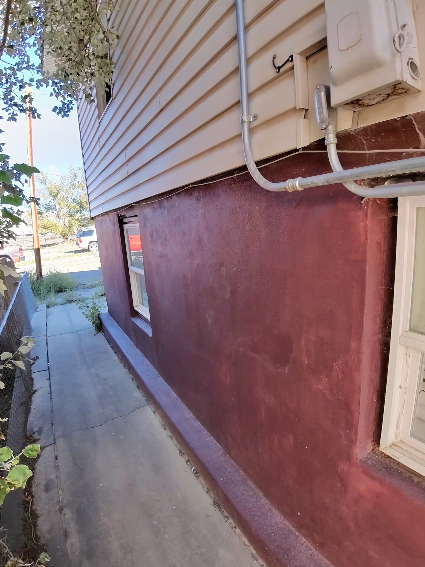 Freshly coated foundation wall along a side walkway of a home.