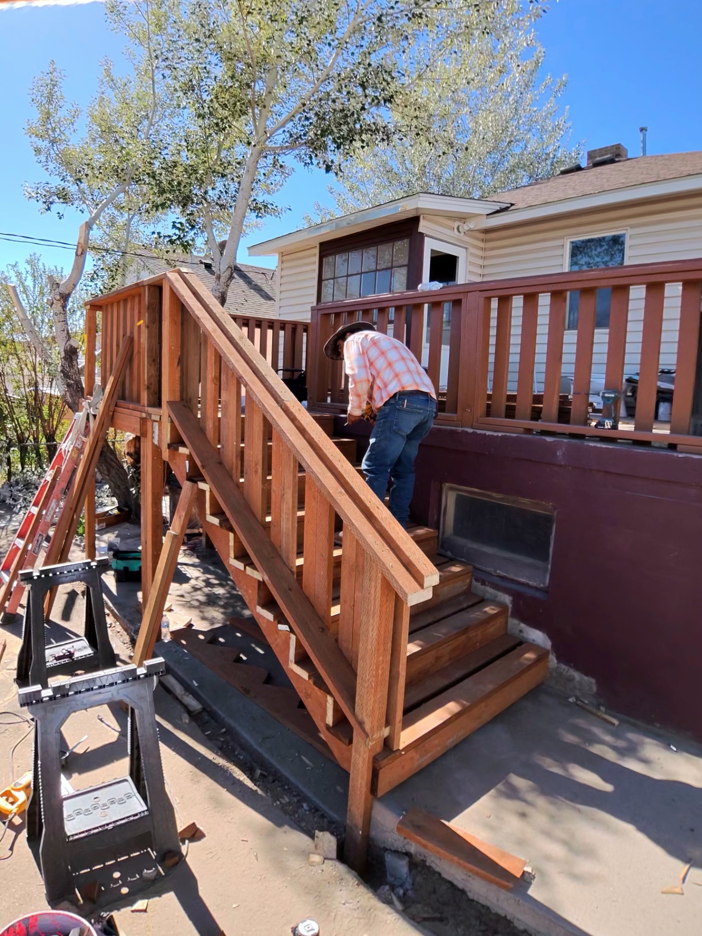New wood stair treads and handrail being installed on a rebuilt residential deck.