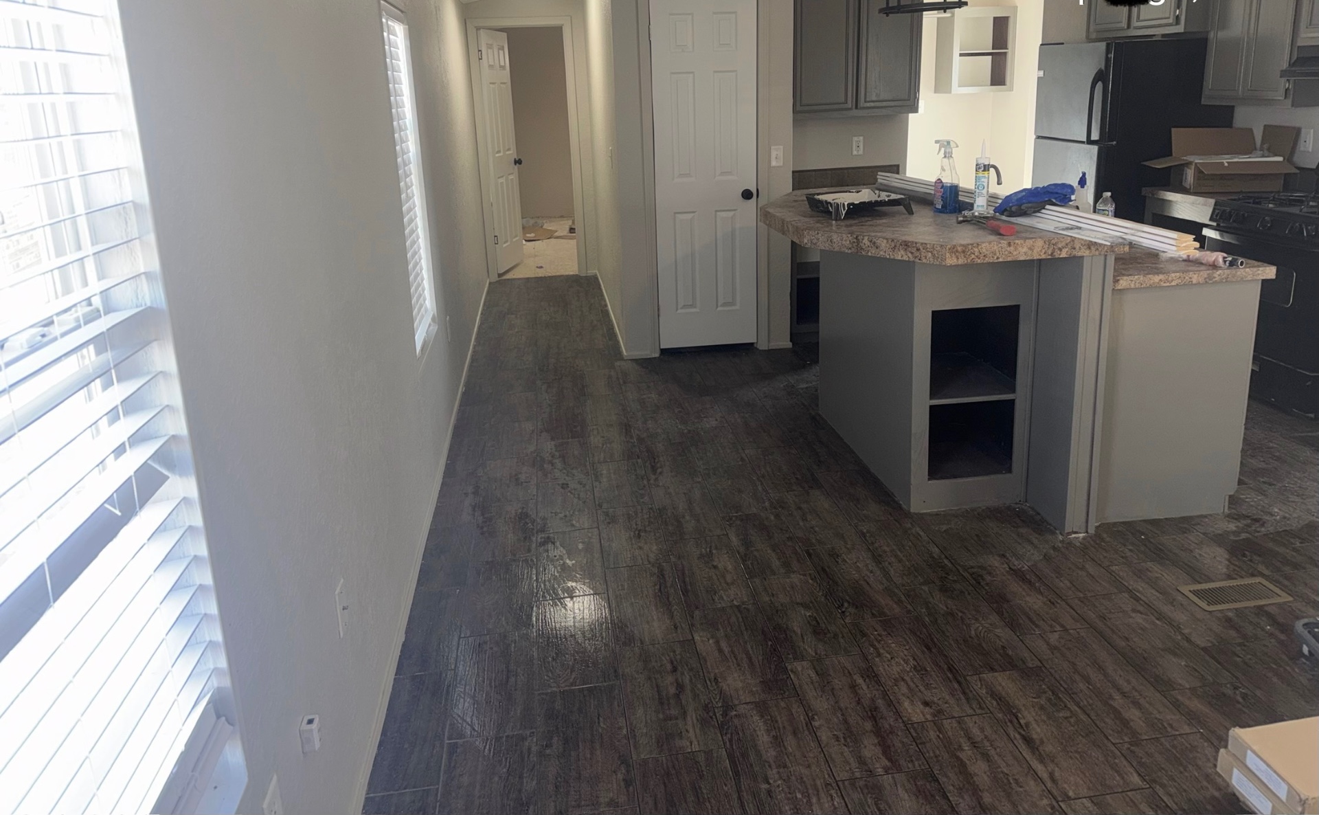 Remodeled residential hallway and kitchen area after JJJ completed the property renovation; flooring was completed by others.