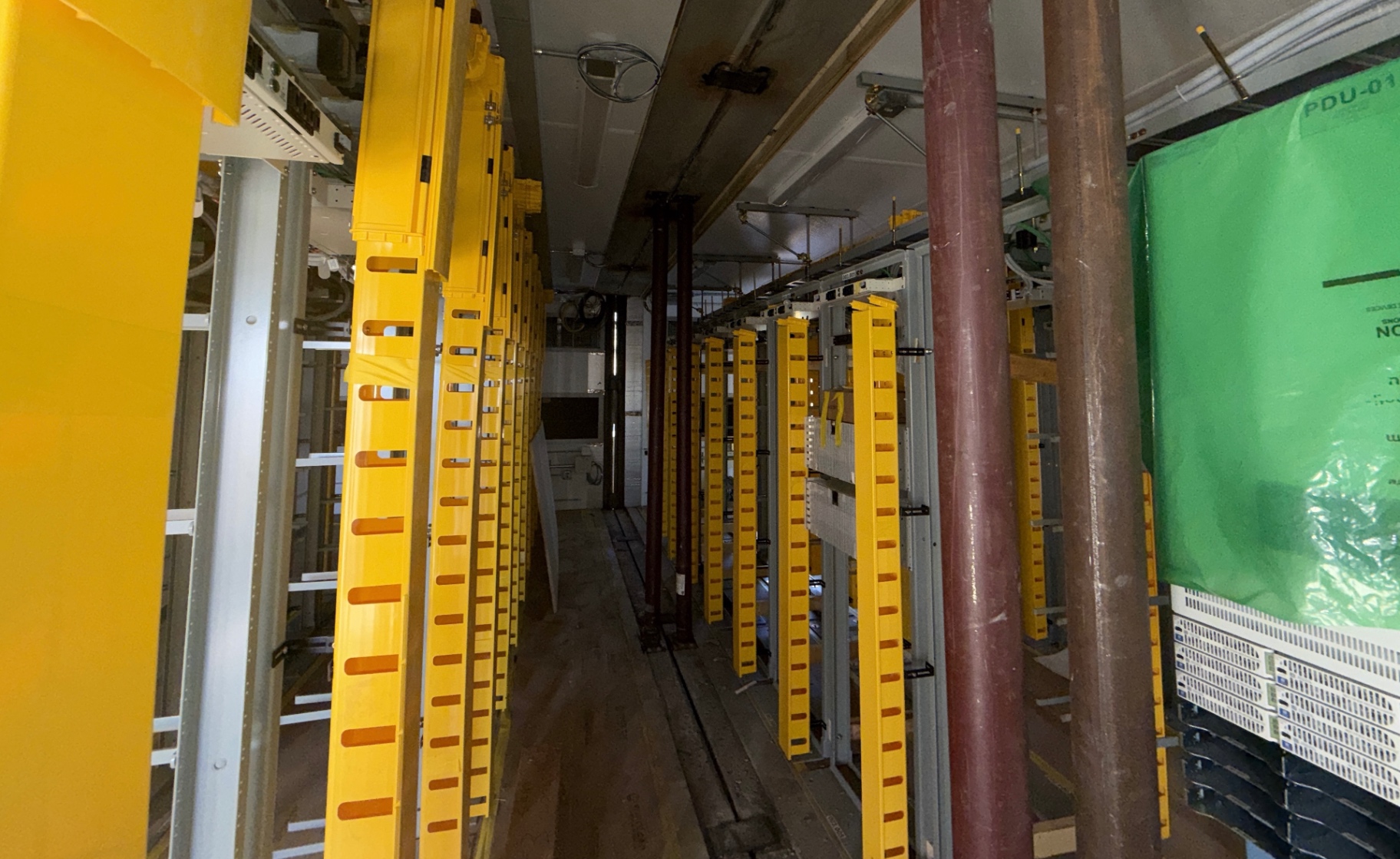Telecommunications facility interior during construction support, with equipment systems installed by other trades visible in place.