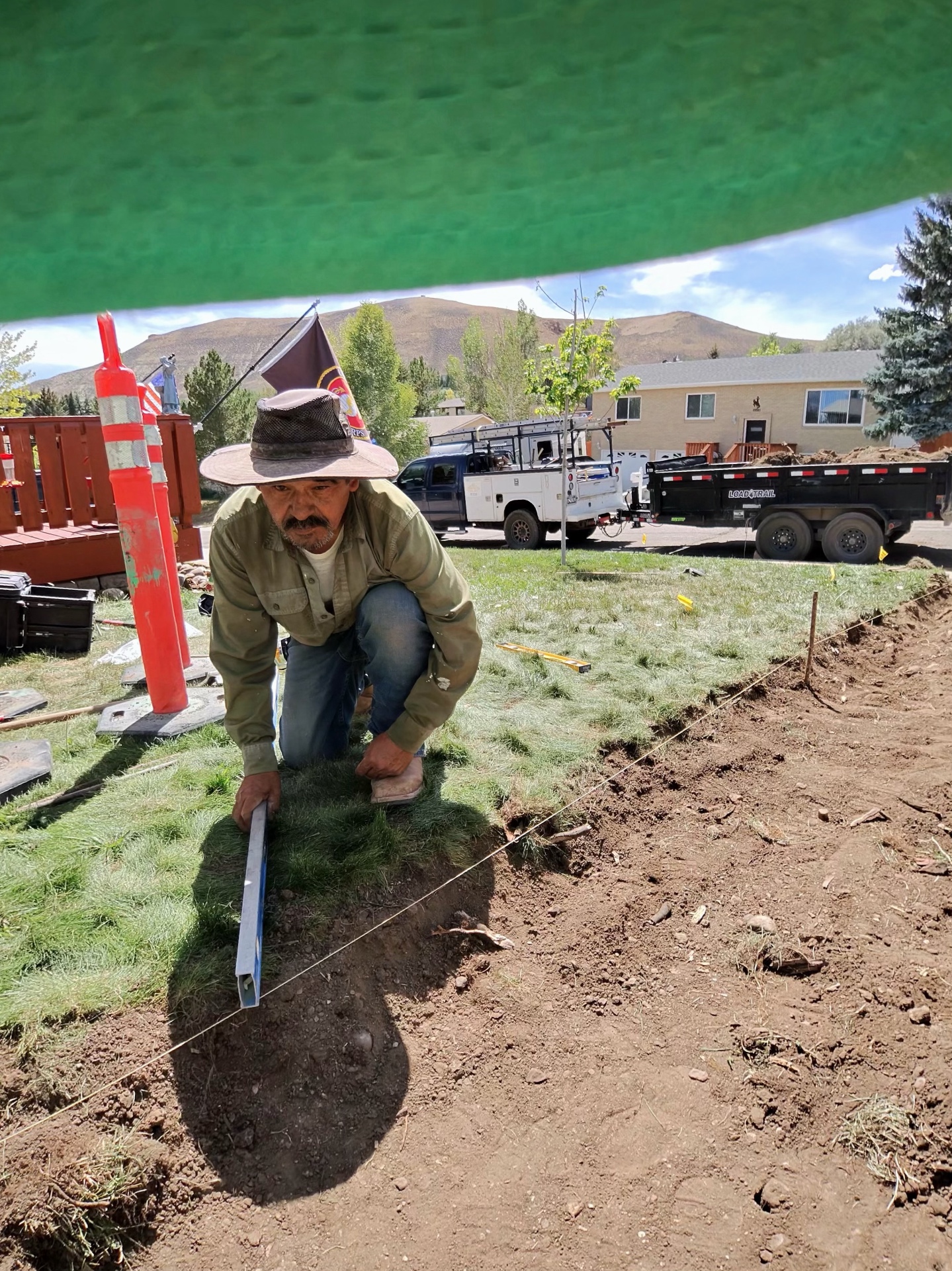 JJJ crew member cutting sod along a string line to set grade for new concrete flatwork.